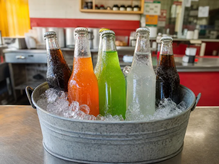 Botellas de refresco de distintos sabores enfriándose en hielo
